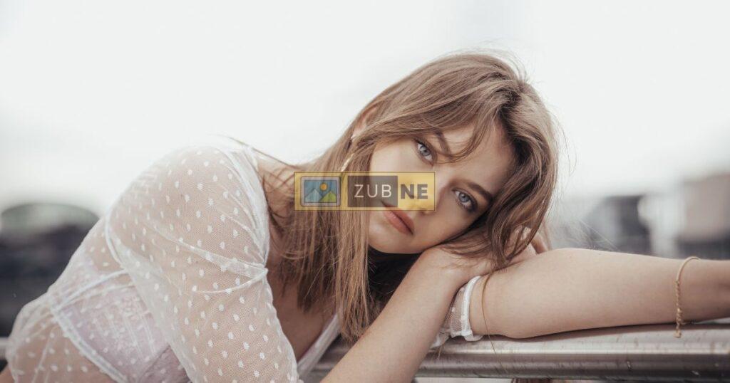 A blonde girl in a sad mood sitting. next to table, sad image on zubne.com