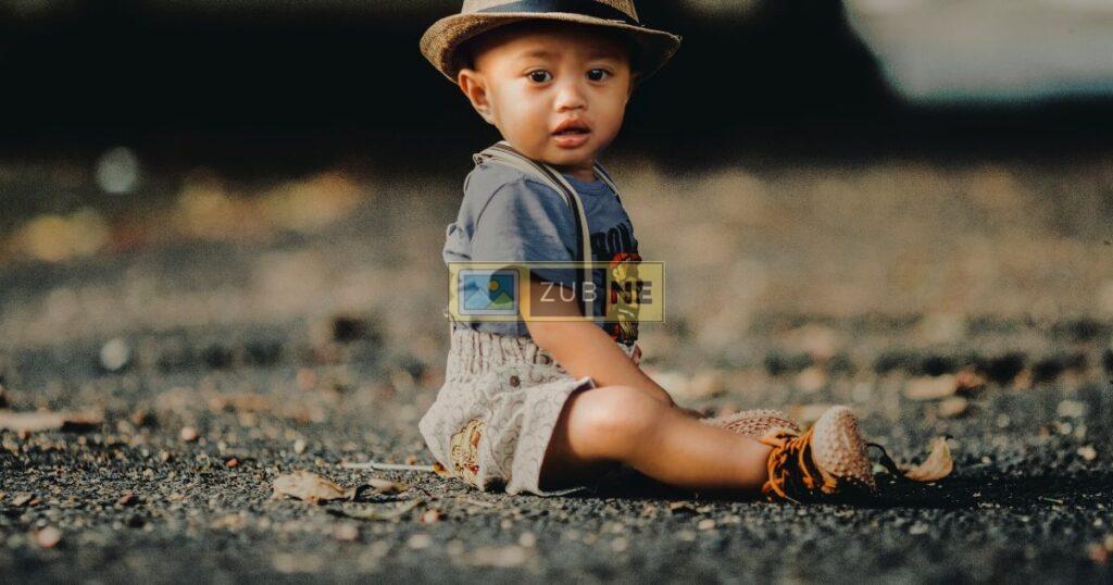 Baby sitting on road wearing hat, baby image on zubne.com