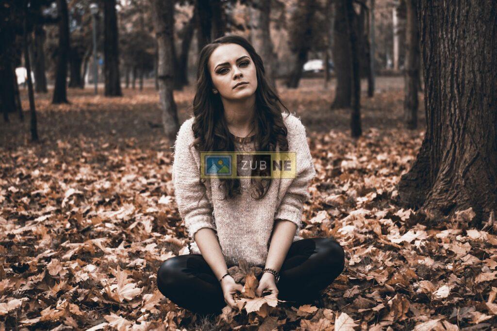 a girl sitting on the ground in a sad mood in the middle dense forest in spring season, sad images on zubne.com