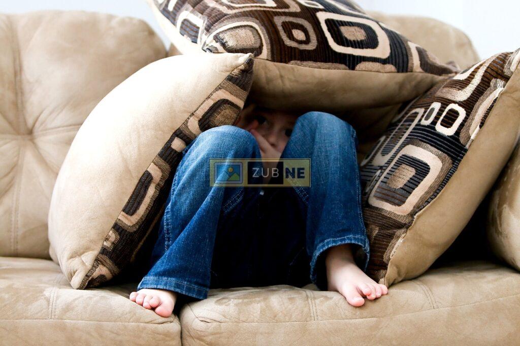a girl sitting on a couch in a sad mood has three pillows on her, sad images on zubne.com