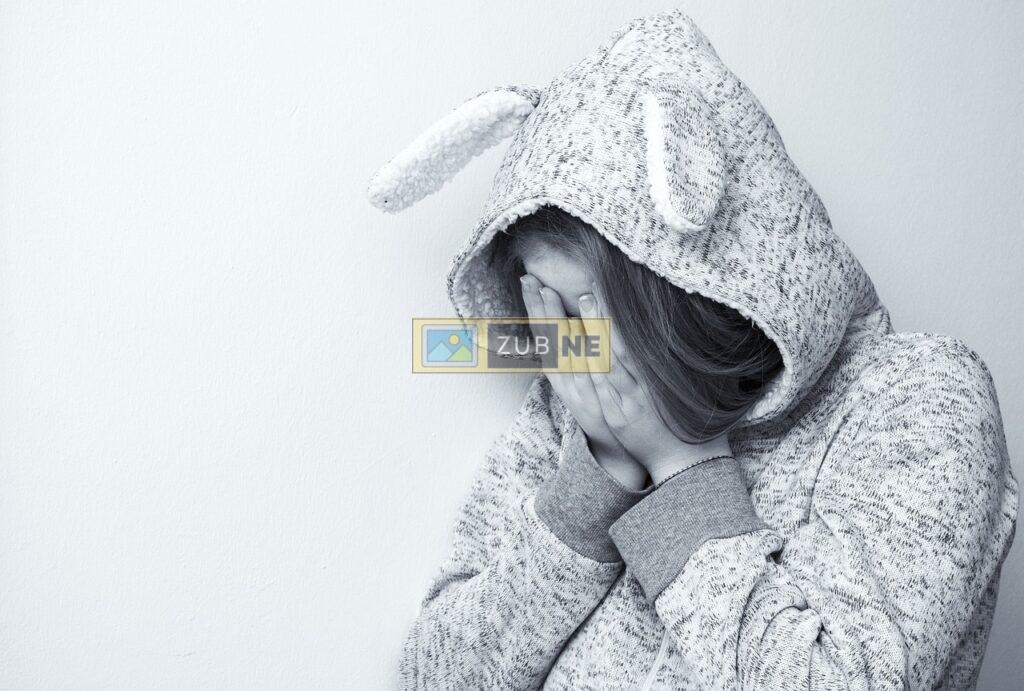 a girl in a sad mood wearing a grey rabbit hoodie and has put her both hands on the face, sad images on zubne.com