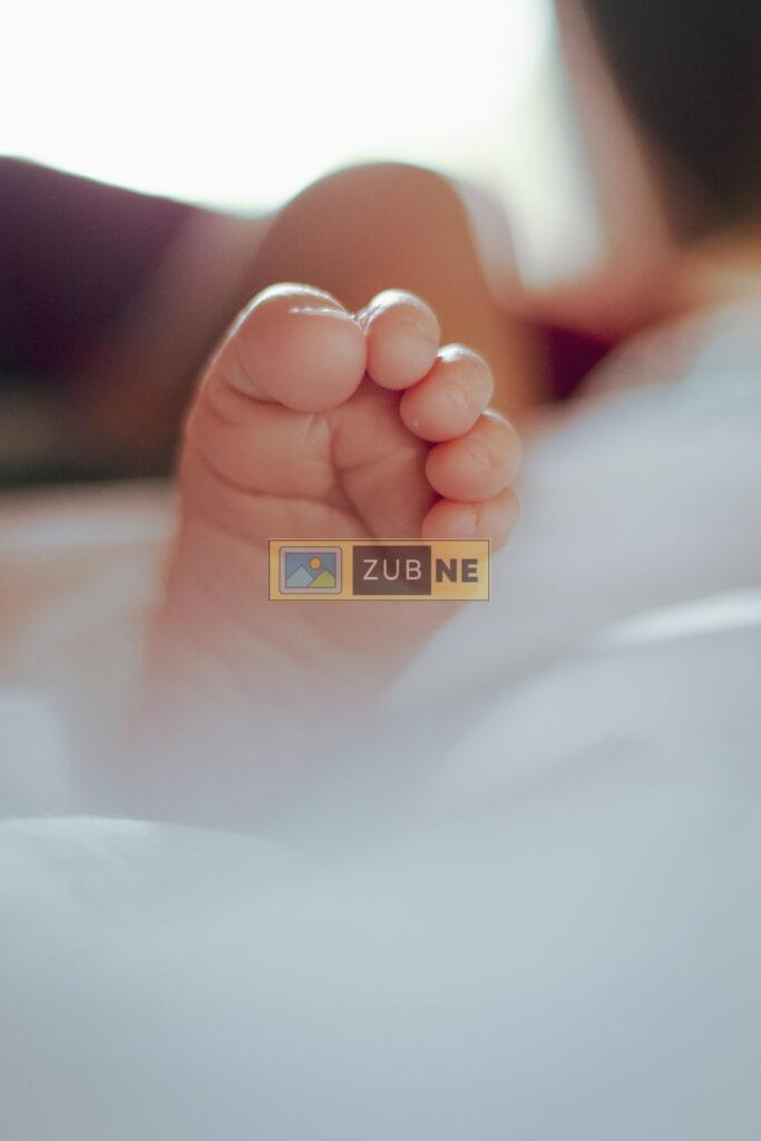 free baby images. A small feet of a new born baby. the baby is lying on the bed.