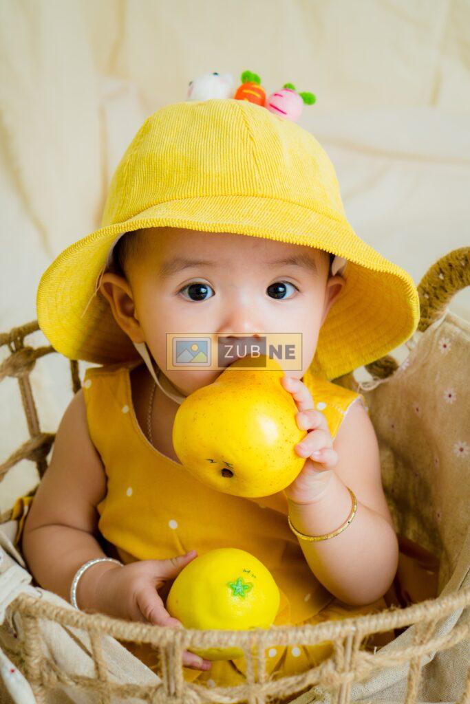 free baby images. A baby wearing yellow dress having a toy in his hands